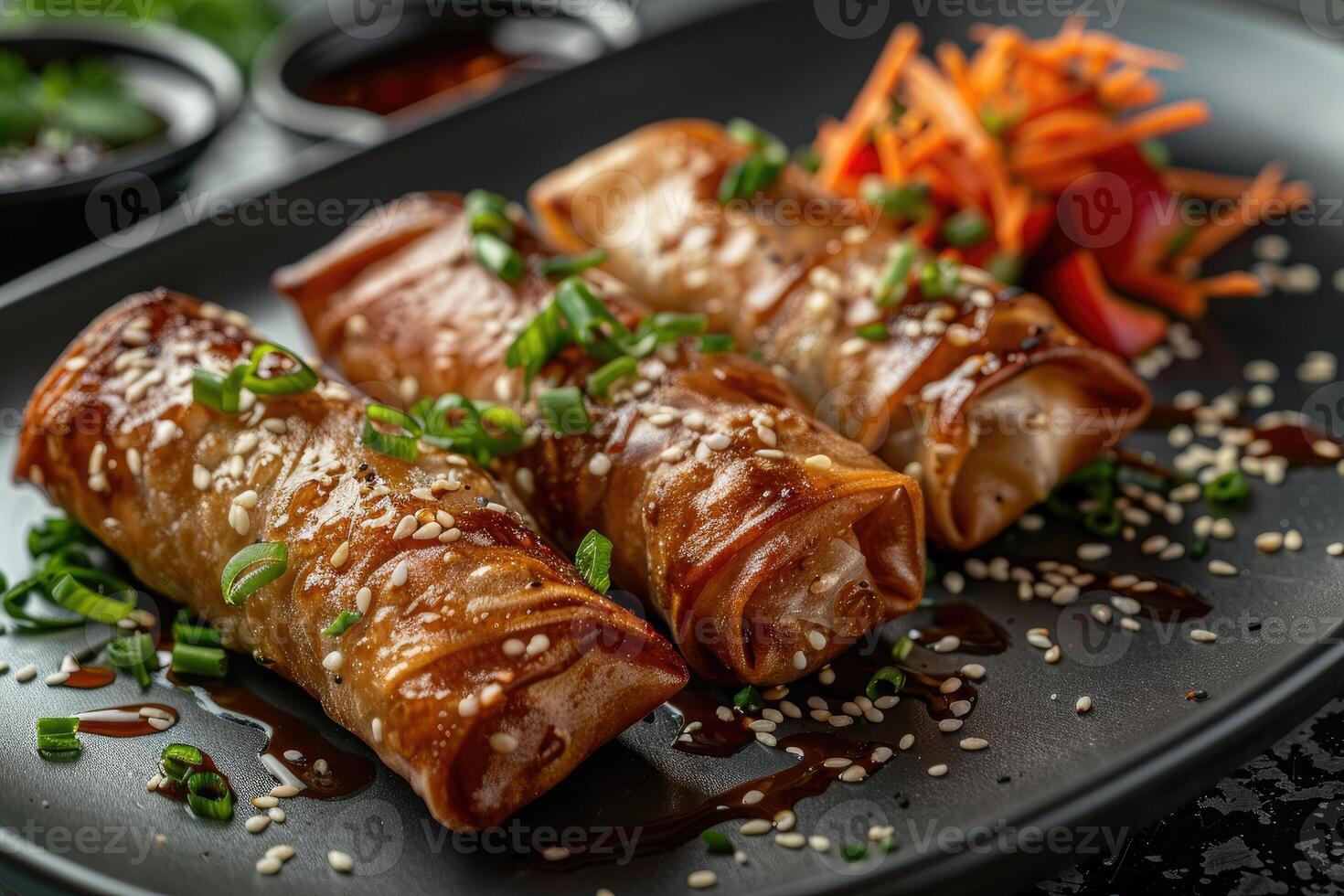 A plate of delicious spring rolls drizzled with sauce and garnished with green onions and sesame photo