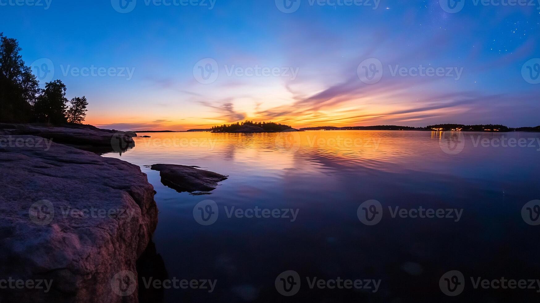 Serene sunset over calm lake reflecting vibrant colors in sky, rocky shoreline. photo