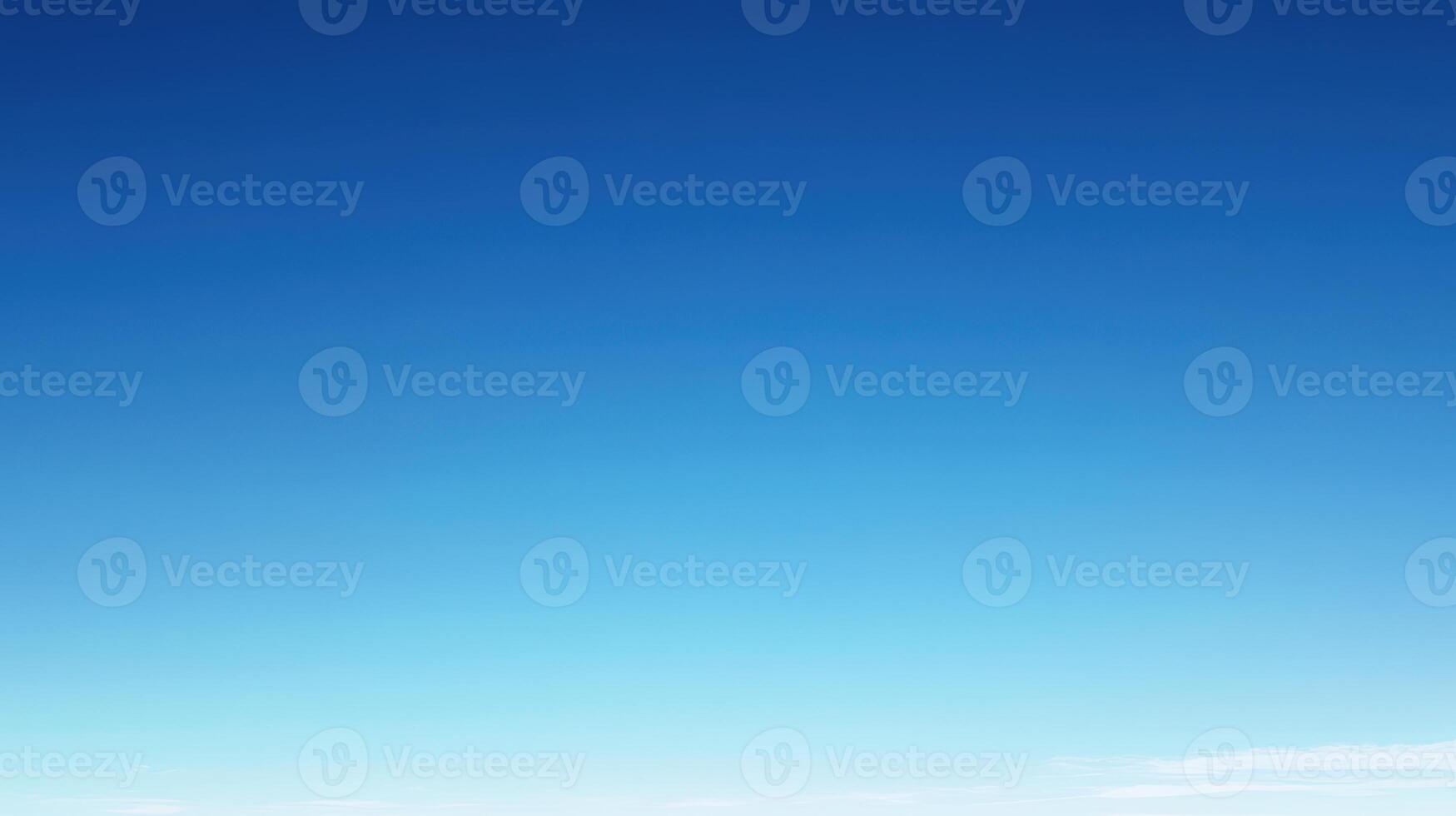 A clear blue sky with subtle gradient and wispy clouds near the horizon photo