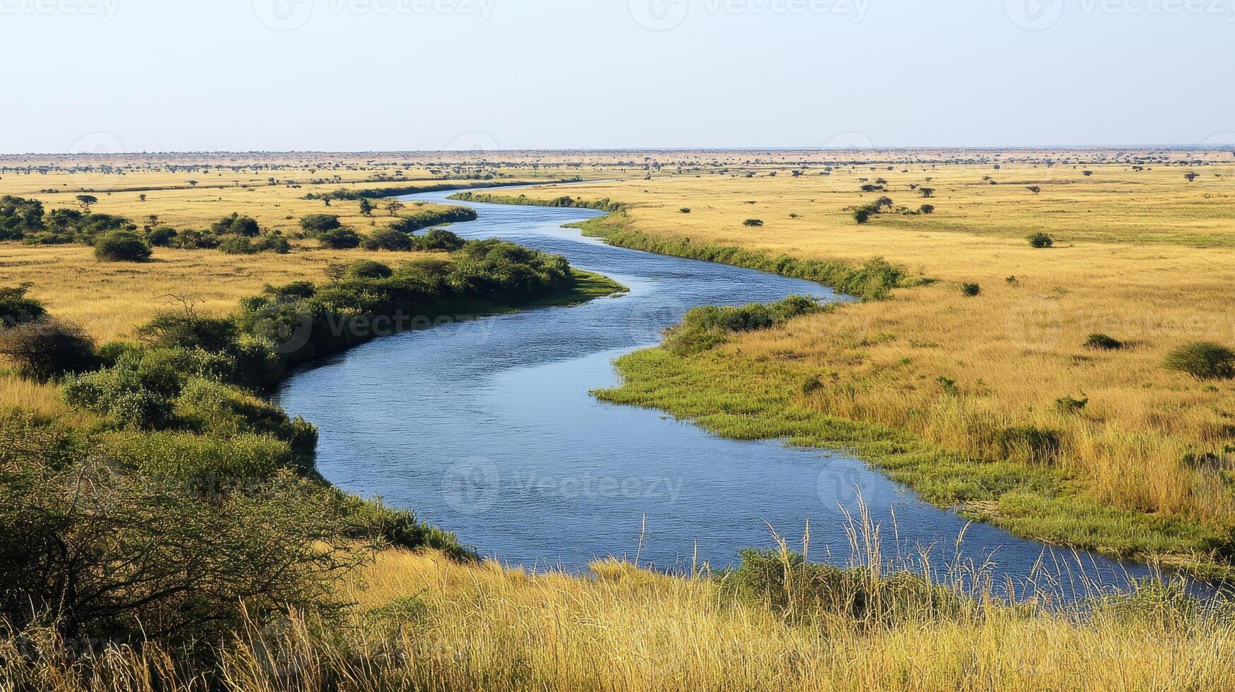 A serene river winding through a vast golden grassland landscape photo