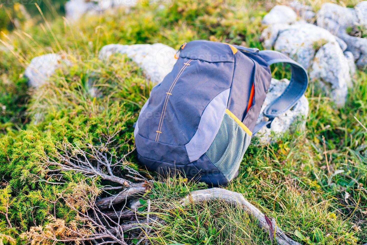 backpack stands on top on the background of mountains stretching to the horizon photo