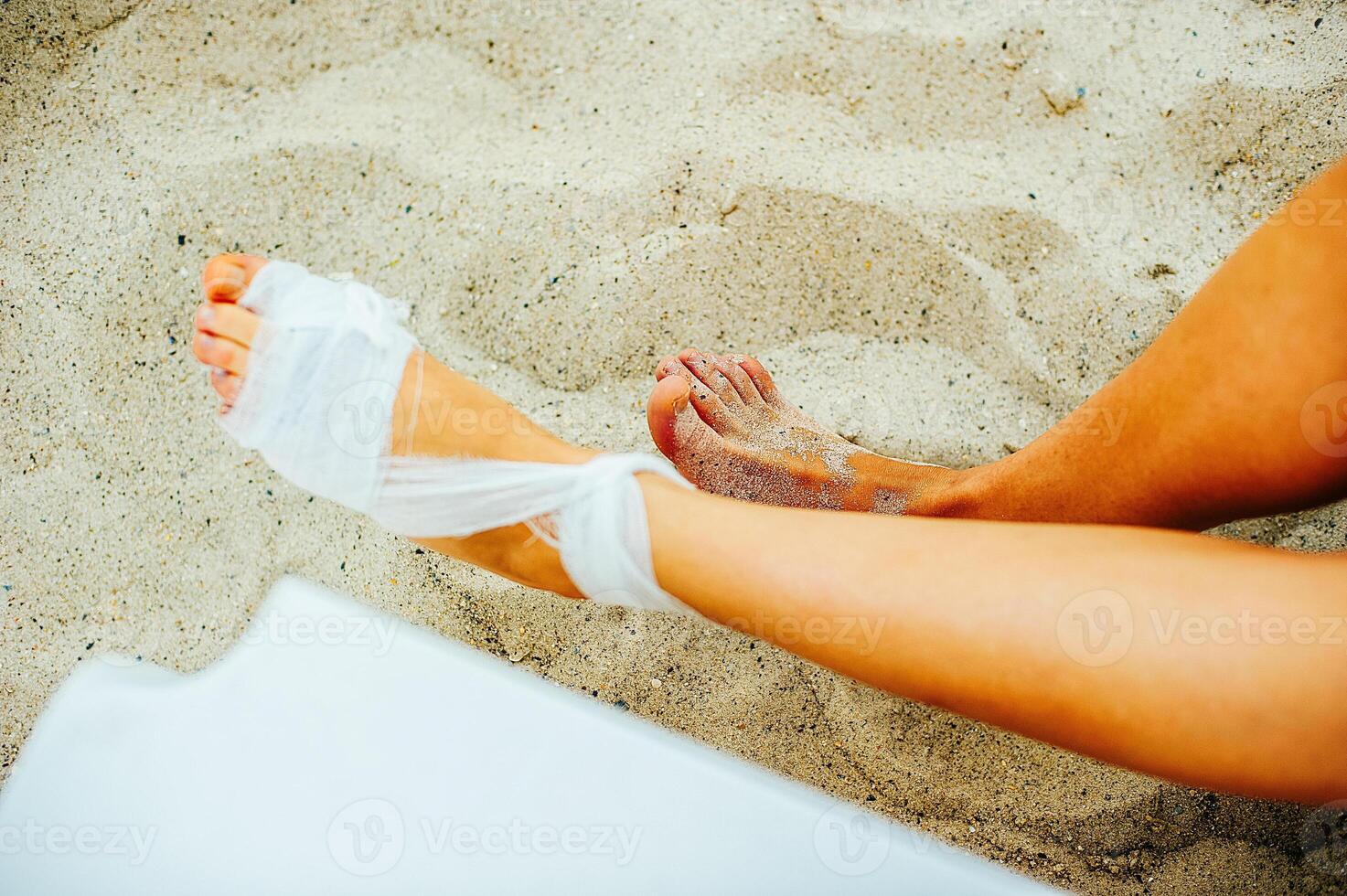 Gauze bandage the treating patients with man is wrapping his foot injury on the beach. photo