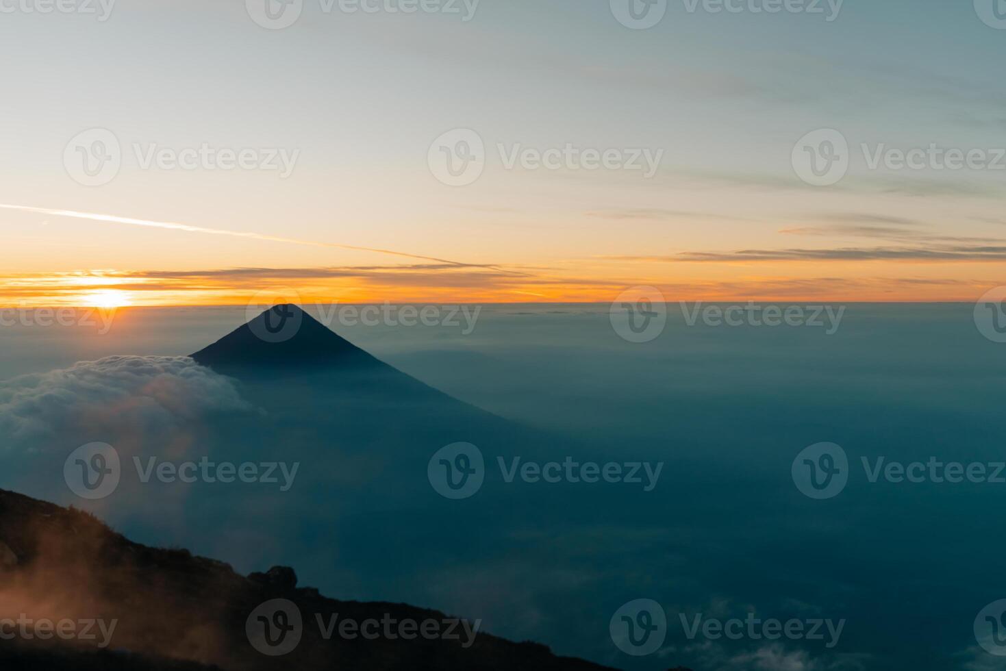Silhouette of volcano de agua at firey orange sunrise seen from the top of volcano de acatenango, guatemala photo