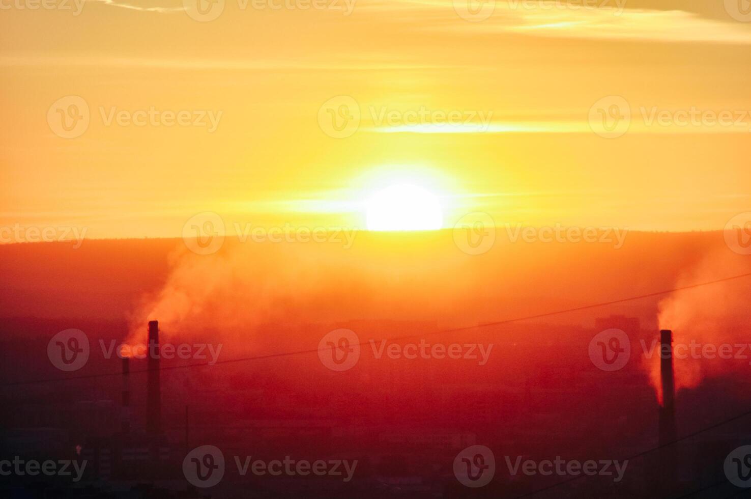 Dark harmful smoke from chimneys of power plant silhouette on sunset clear orange sky photo