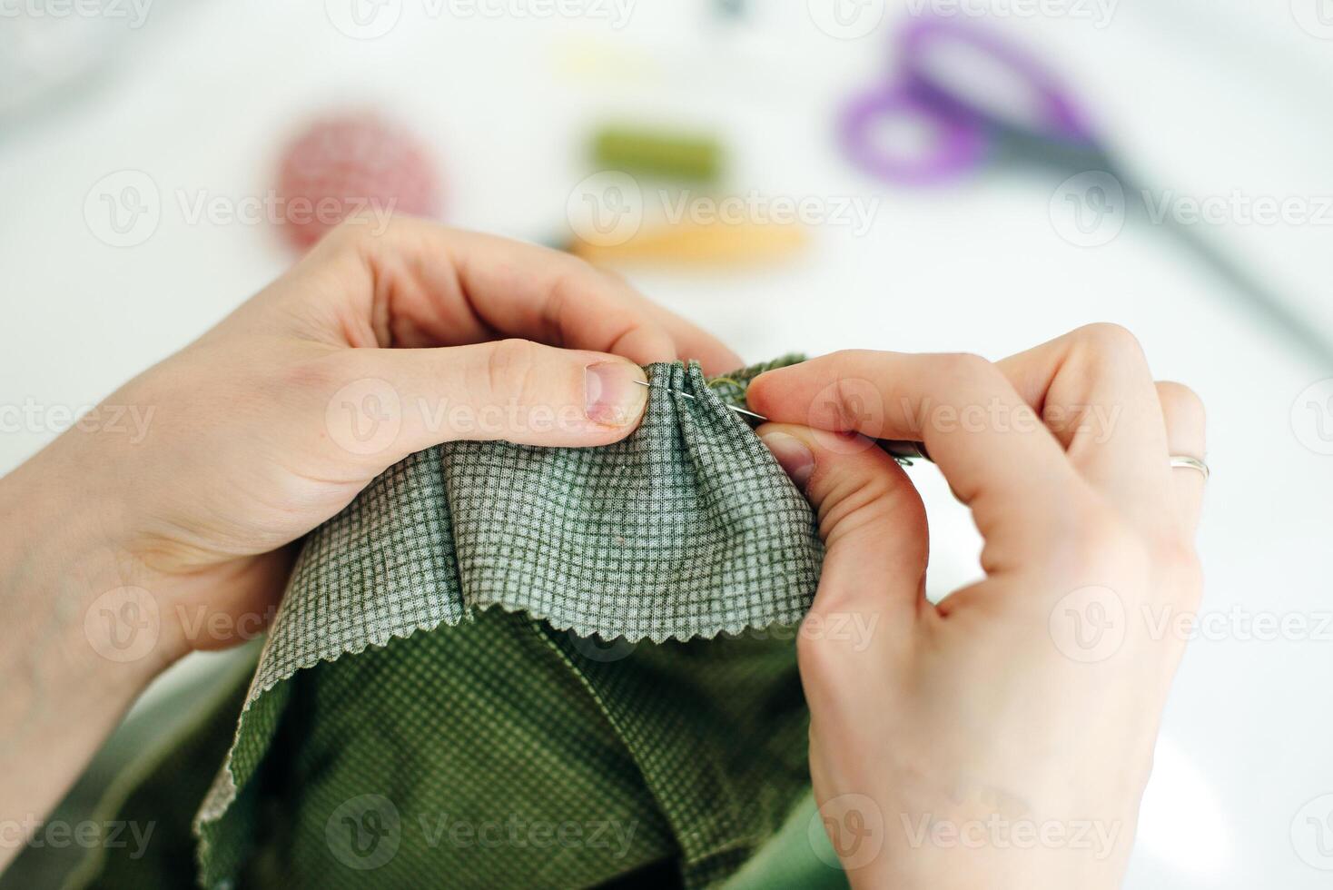 sewer sews up the hole in the pants in studio, photo