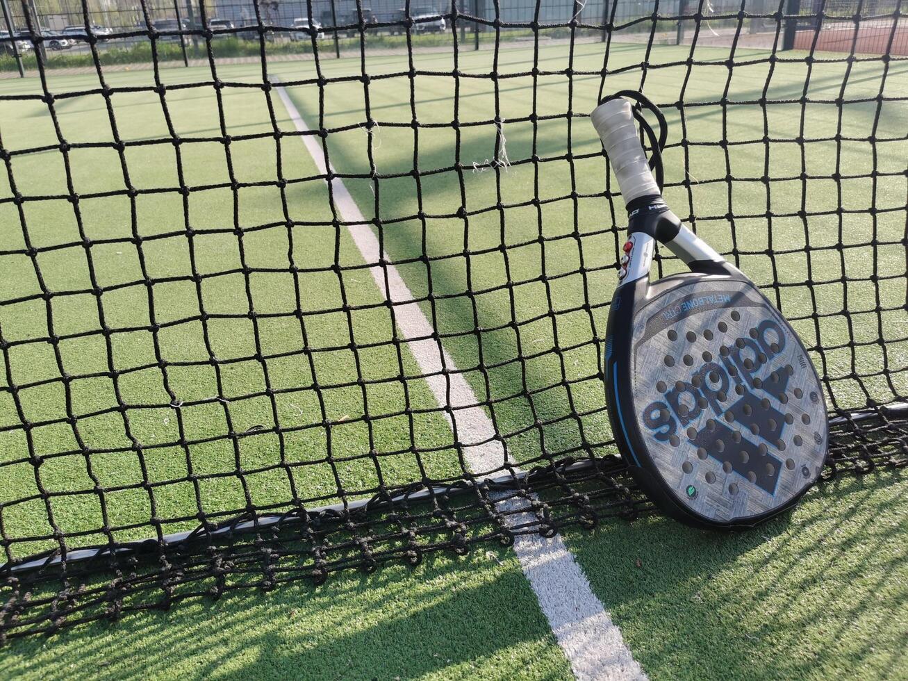 Ukraine Kyiv, April 11 2024. Padel racket adidas and padel ball on a green court photo
