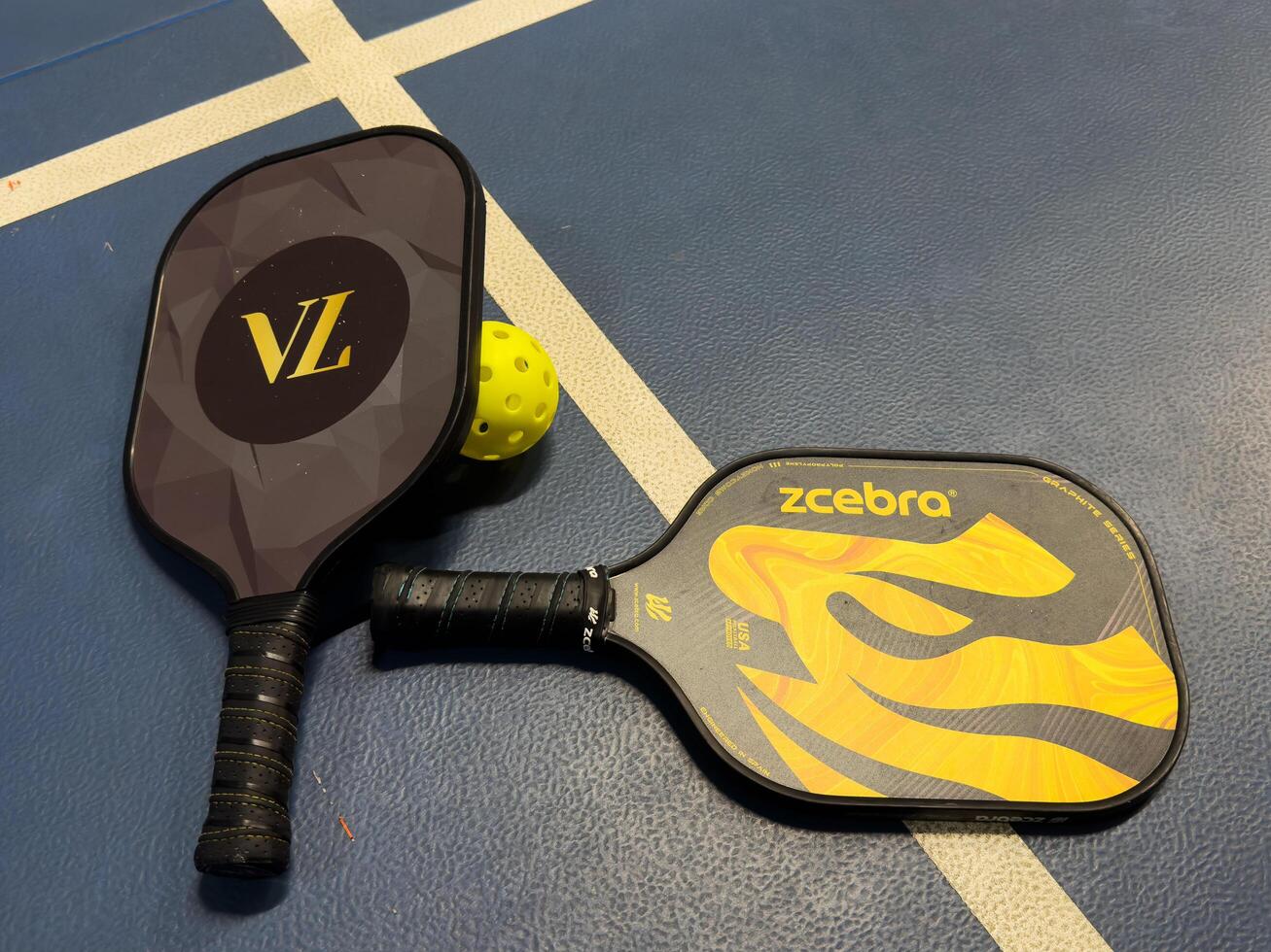 Kyiv, Ukraine - December 14, 2024 Pickleball tennis racket on the court. Blue background with copy space. Sport court and ball. photo