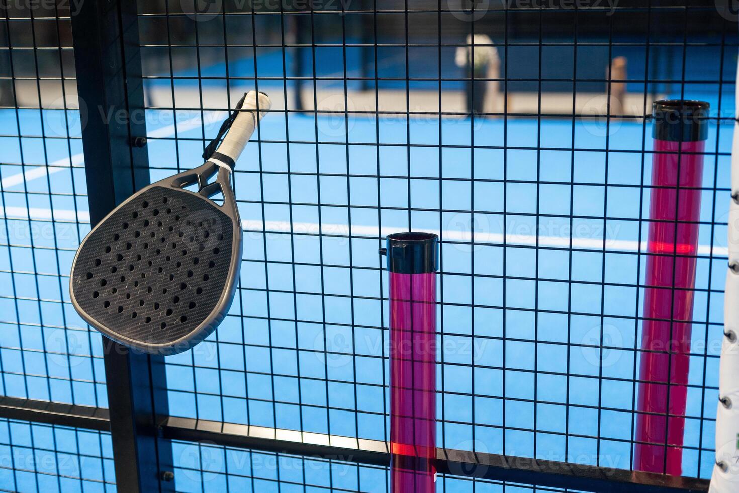 Padel Racket Strung in the Outdoor Structure Surrounding the Playing Field and Players in the Background. photo