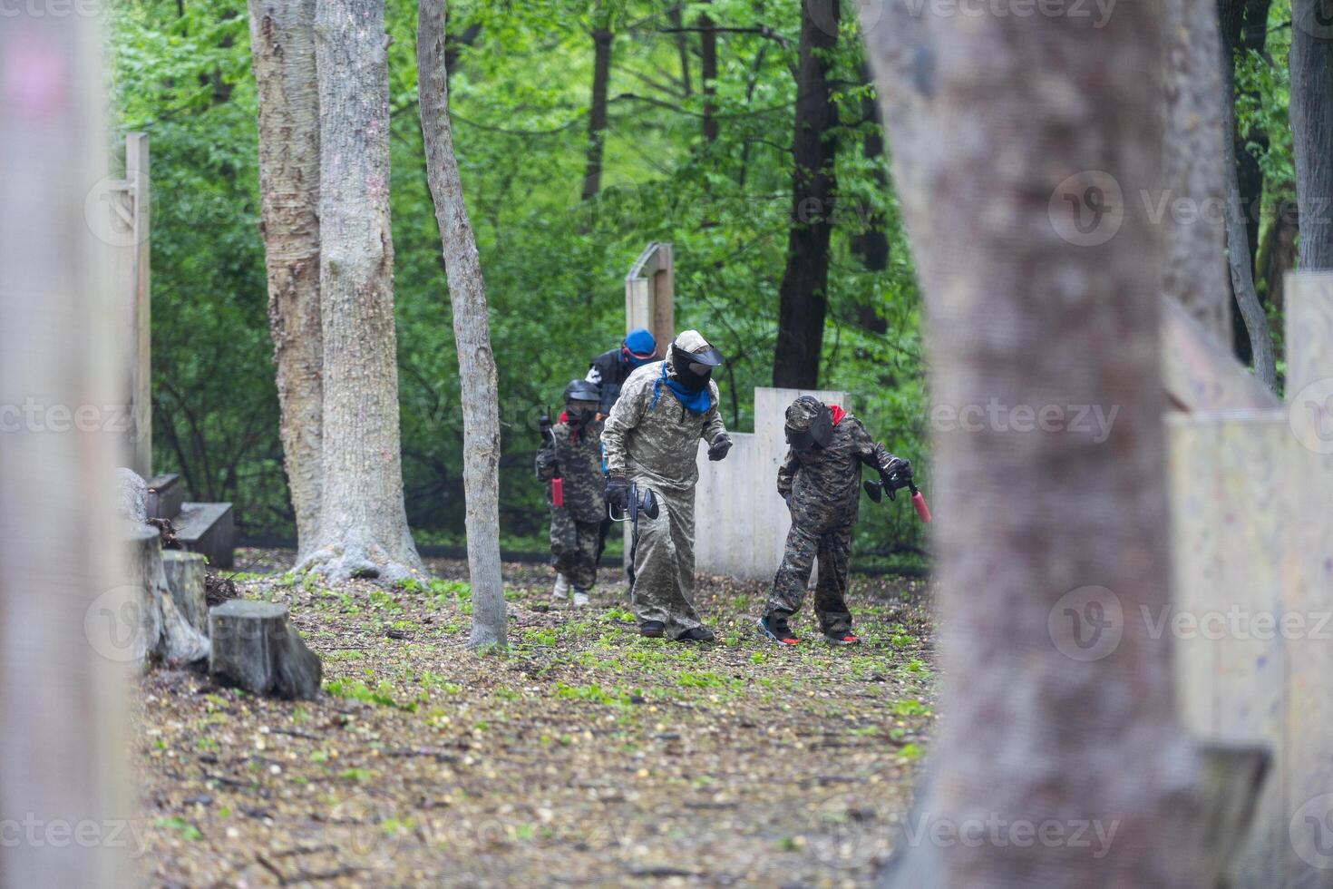 Warriors in camouflage and masks playing paintball photo