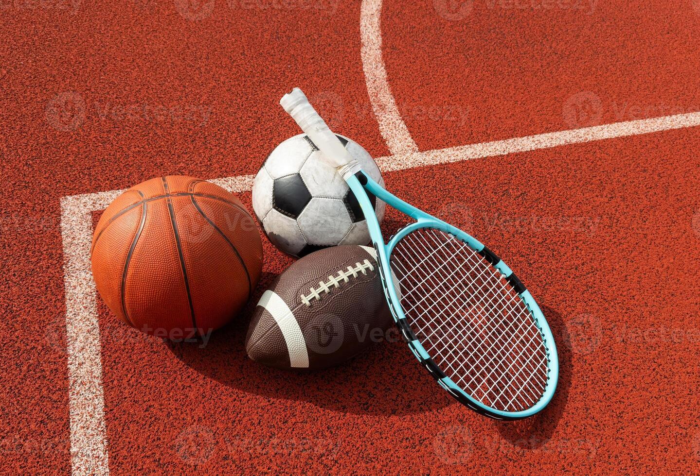 A variety of sports equipment including an american football, a soccer ball, a tennis racket, a tennis ball, and a basketball photo