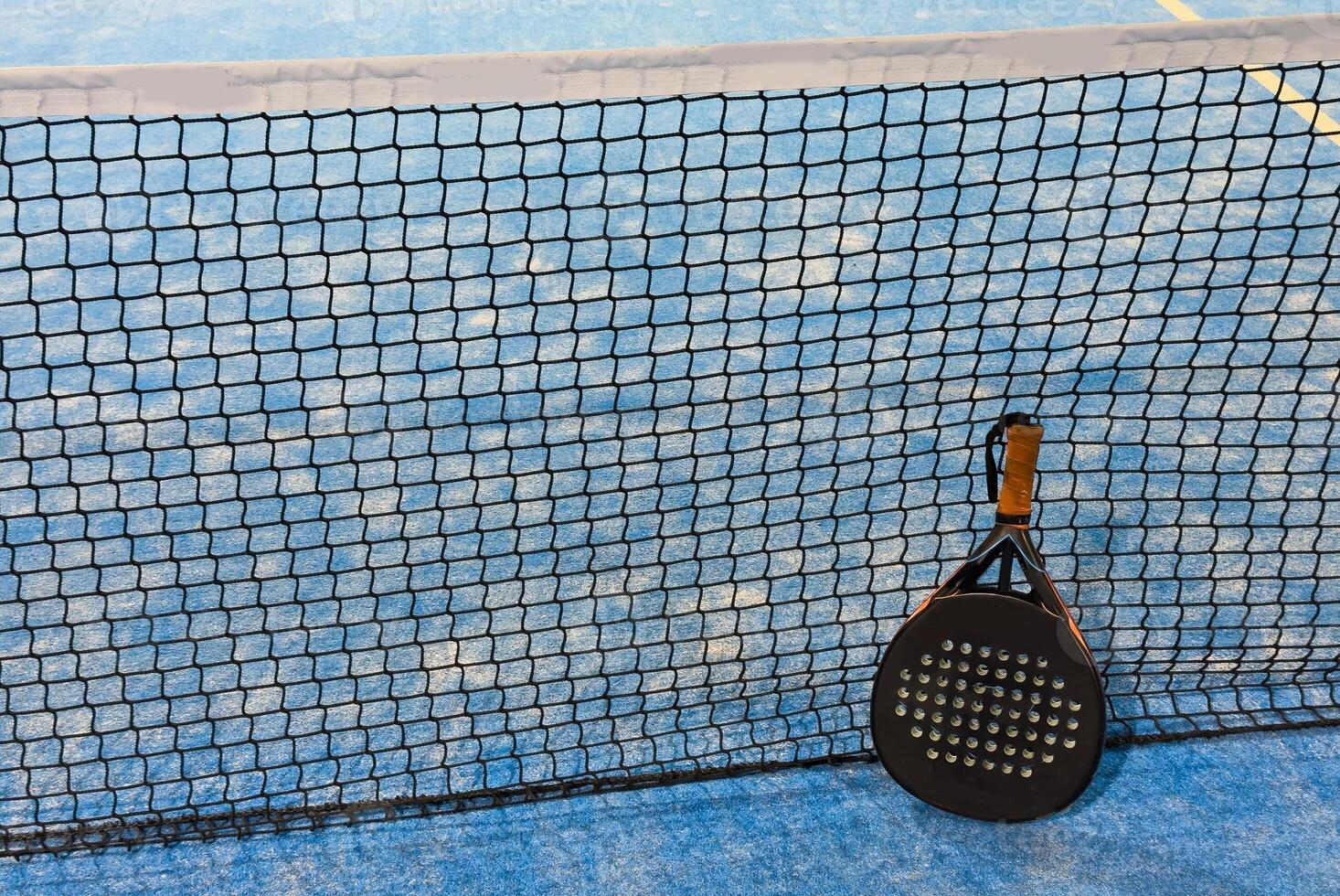 Paddle racket with a ball ready to play the fastest growing sport in recent years worldwide. Padel court in summer, the perfect time to practice this sporting discipline and release stress. photo