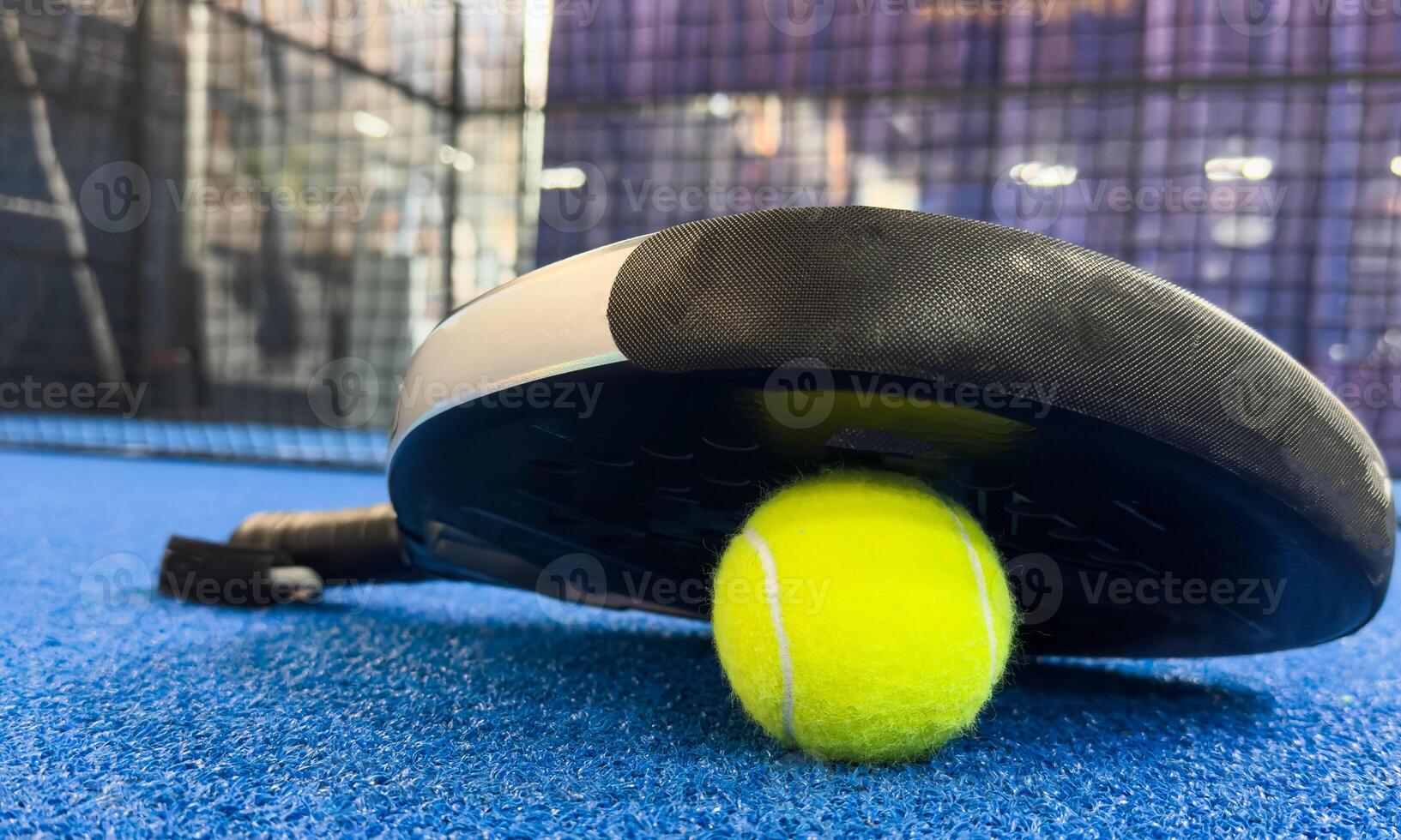 Paddle racket with a ball ready to play the fastest growing sport in recent years worldwide. Padel court in summer, the perfect time to practice this sporting discipline and release stress. photo
