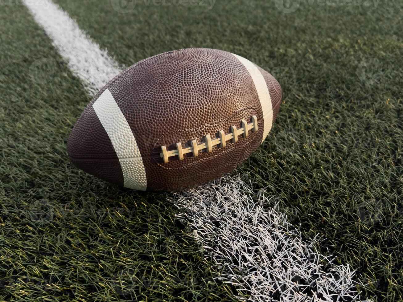 American football ball on green grass field background. photo