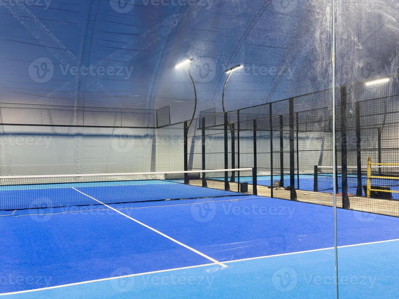 Under a vast modern structure, newly installed padel courts. Centered is the entrance to the courts, on one side, photo