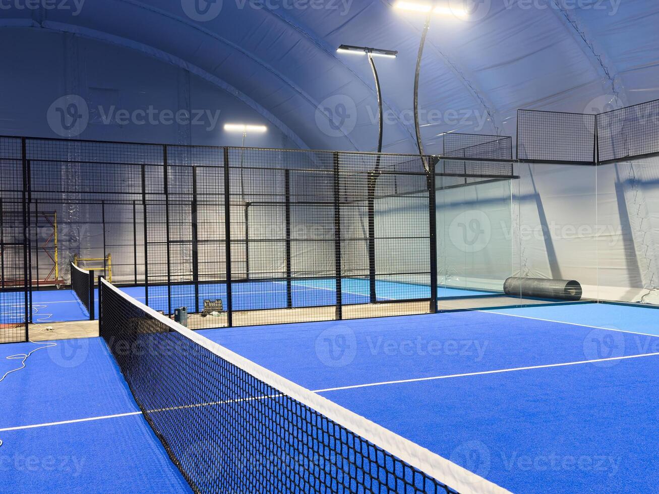 blue court for padel with construction created by mesh and the glass back walls. photo