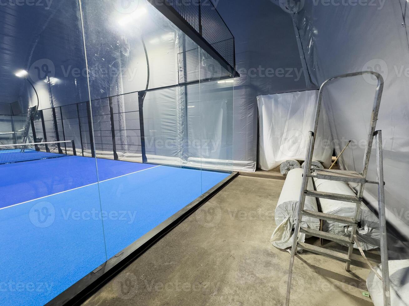 Under a vast modern structure, newly installed padel courts. Centered is the entrance to the courts, on one side, photo