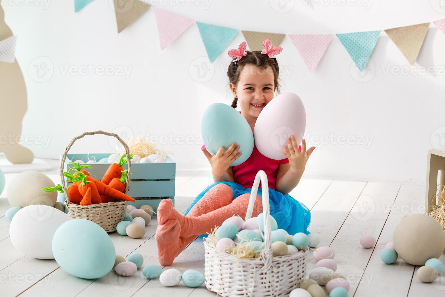 Getting ready to Easter. Lovely little girl holding an Easter egg and smiling with decoration in the background photo