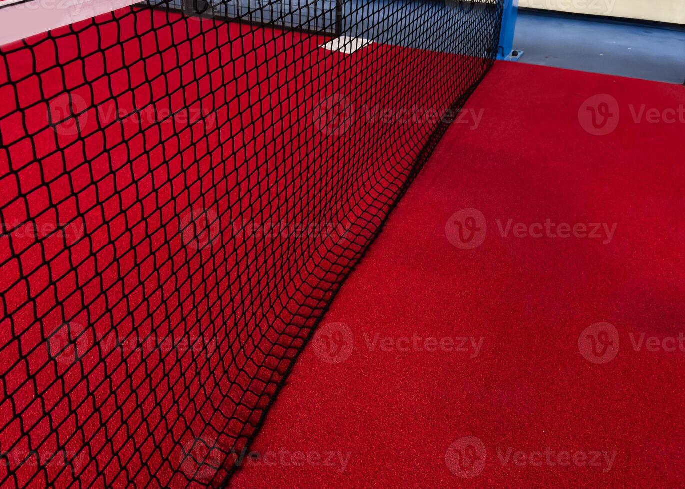 View of the net and the centre line of a red paddle tennis court. Racket sports photo