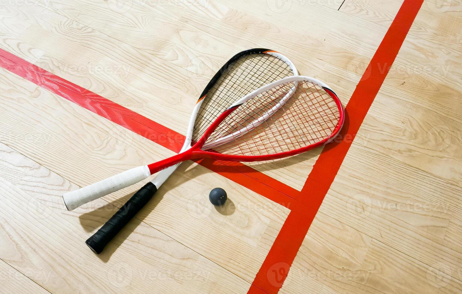 Squash rackets and ball on court floor, top view photo