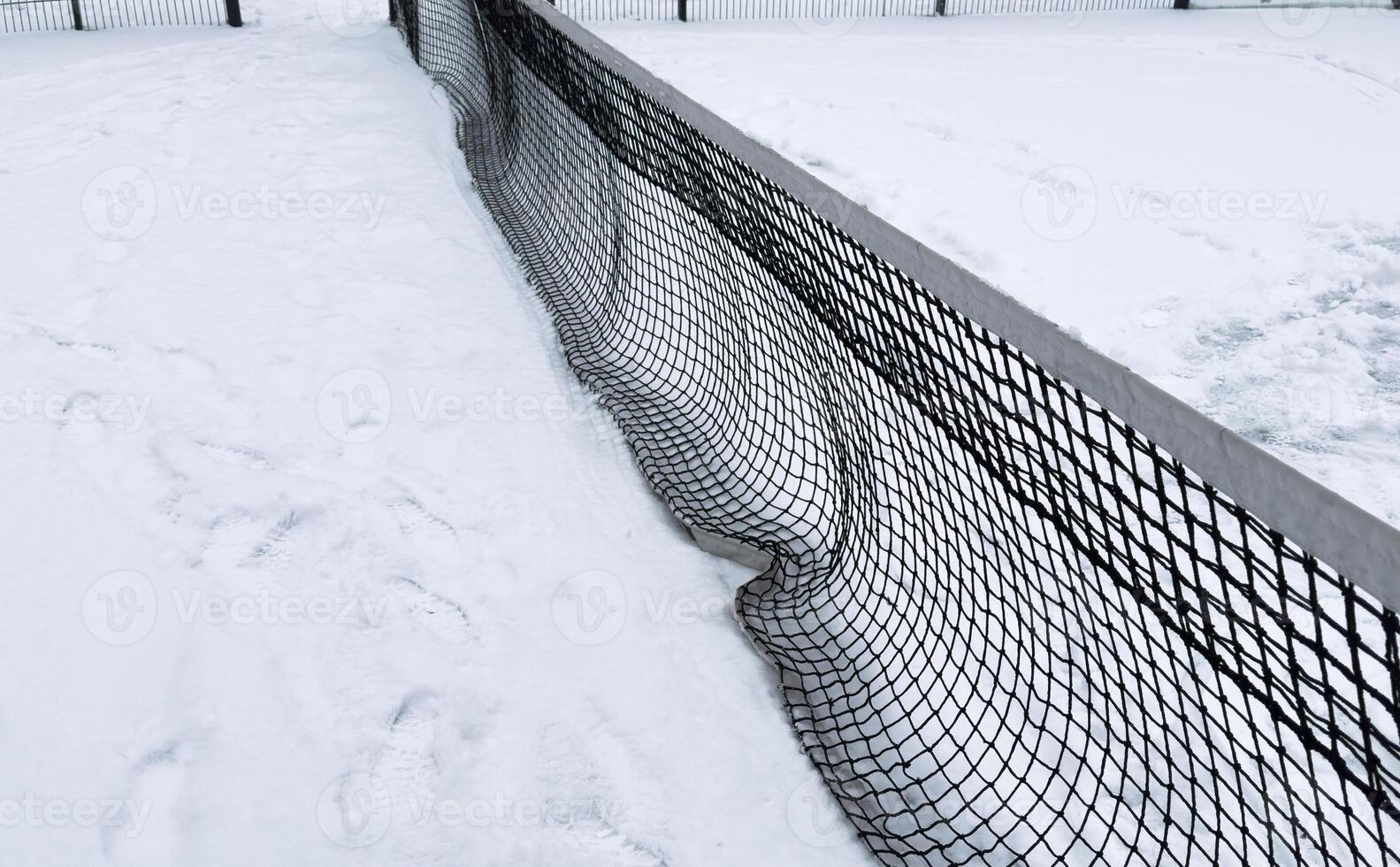 Row of snow covered tennis court nets, in a weather delay concept, with space for text photo