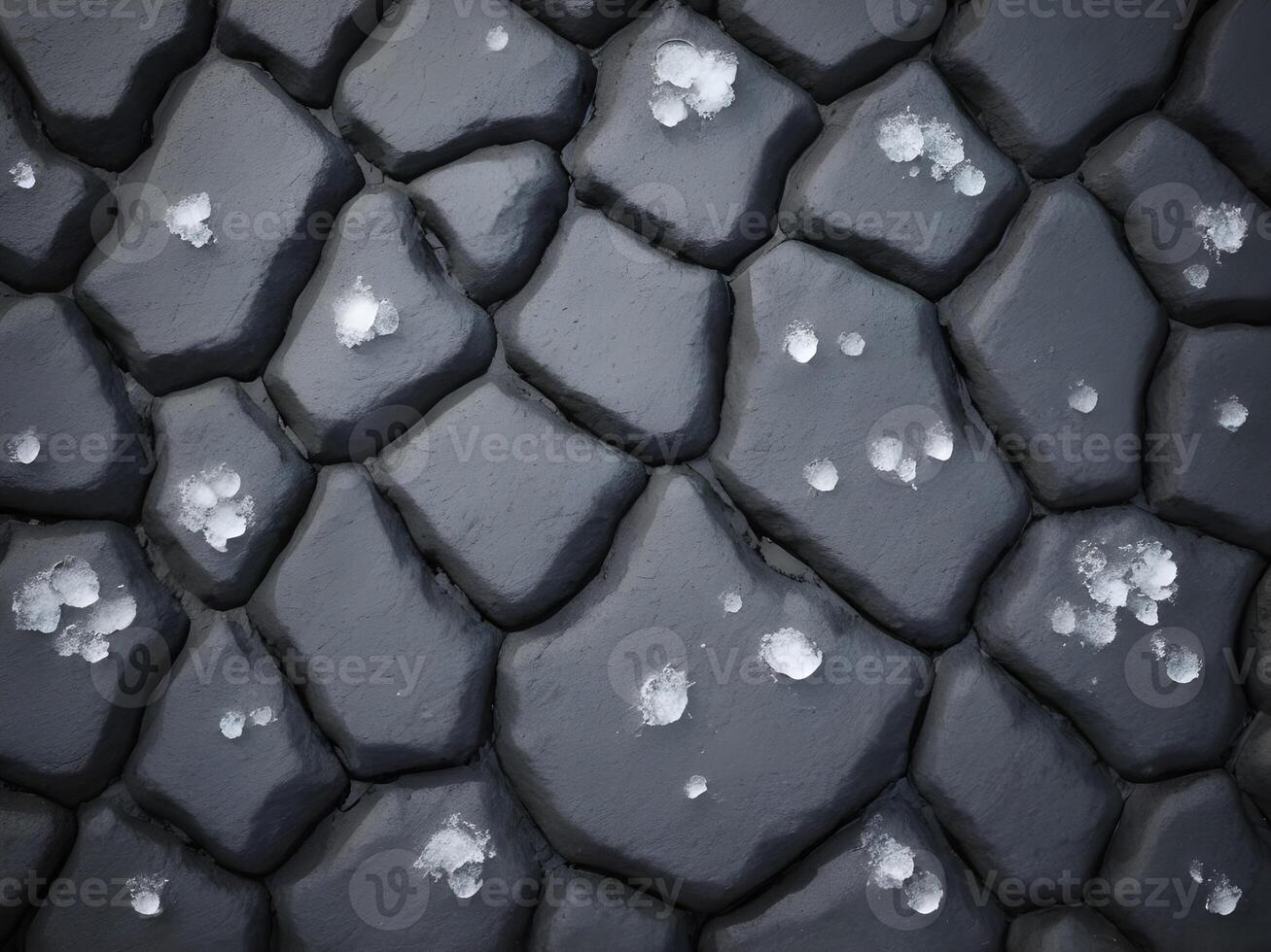 A detailed photograph capturing the delicate snowflakes melting over a textured asphalt surface. photo