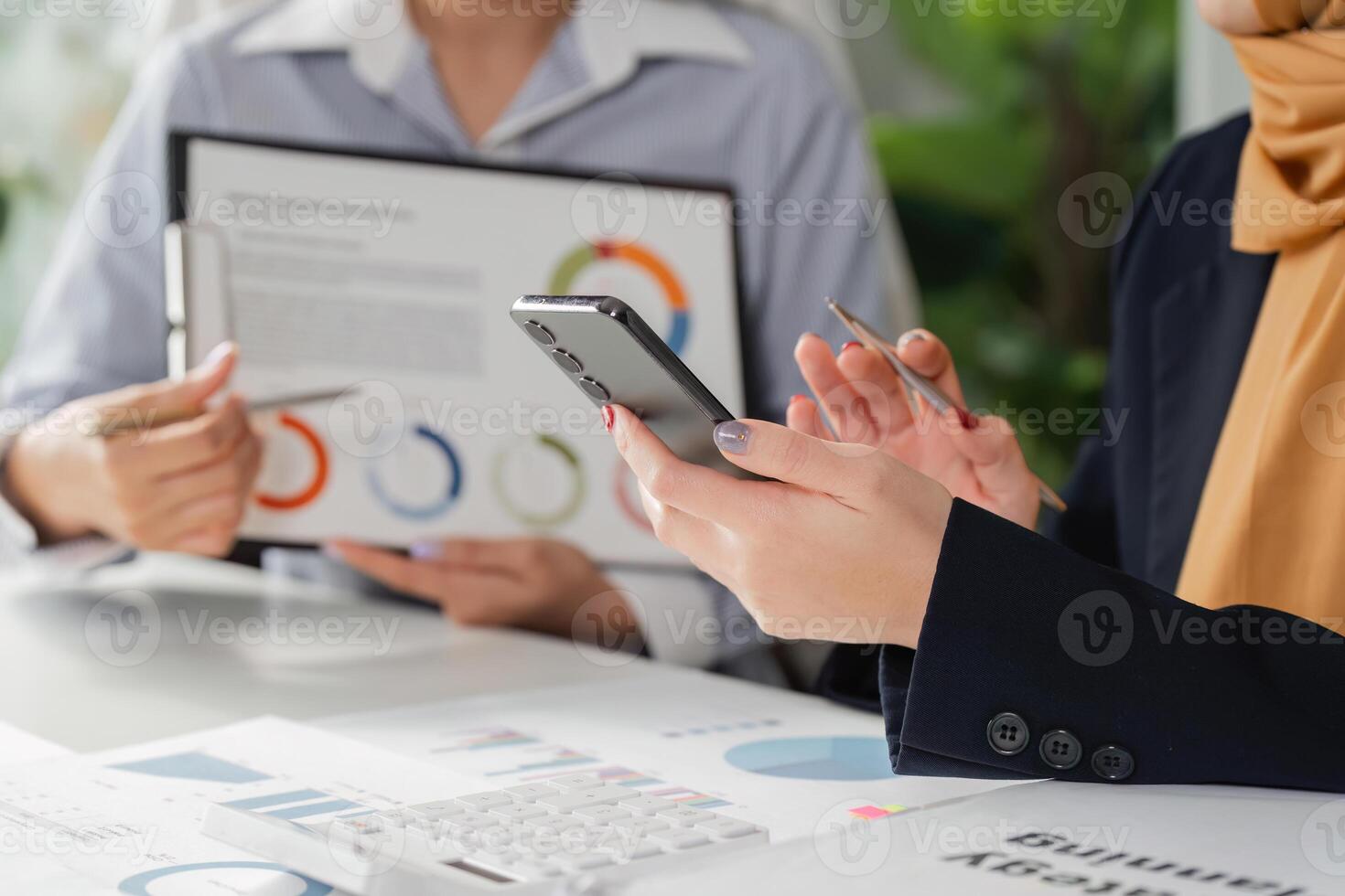 Diverse professionals analyzing financial reports and using a smartphone for strategy planning in the office. photo