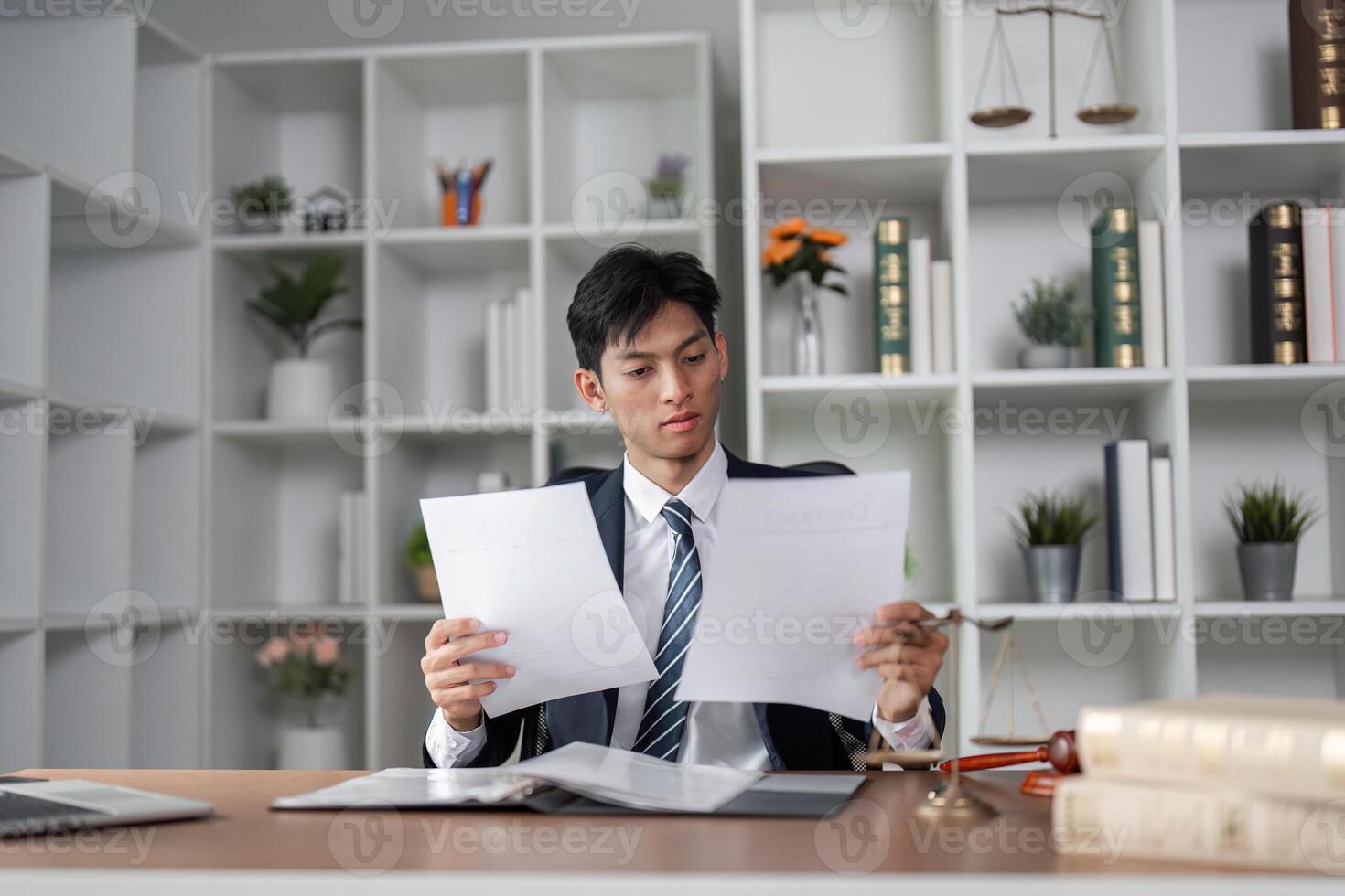 Young professional in suit reviewing documents at desk, analyzing information and making decisions in modern office. photo