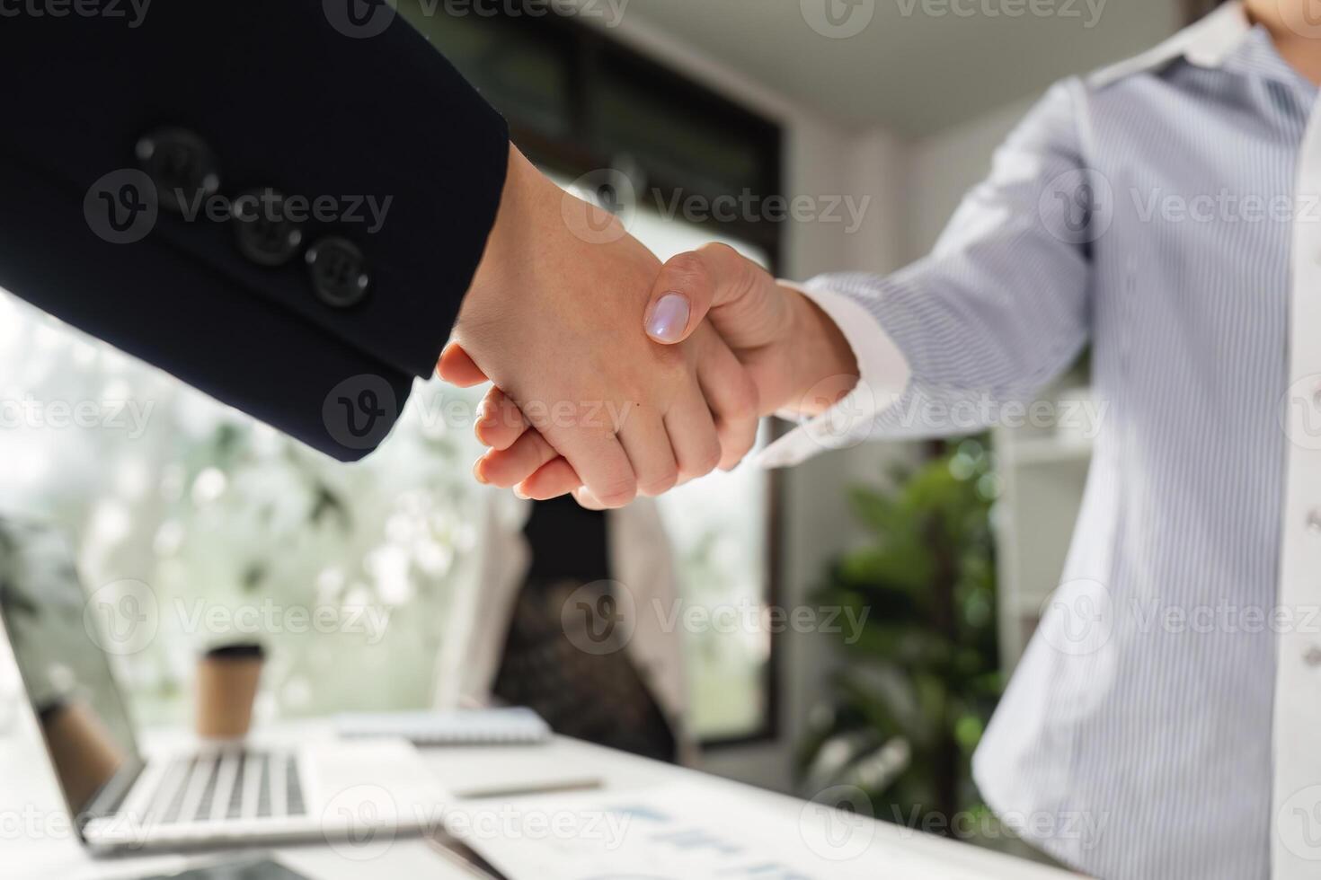 Diverse business professionals shaking hands in office, symbolizing partnership and collaboration in business. photo