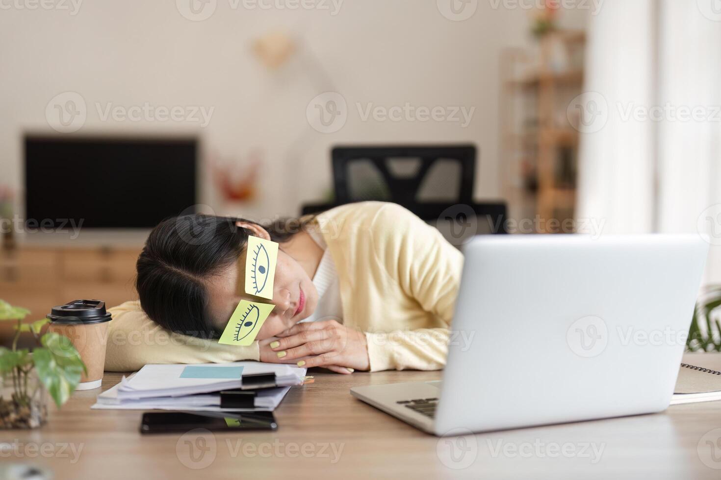 Exhausted woman resting her head on a desk, highlighting the need for a break in a busy workday. photo