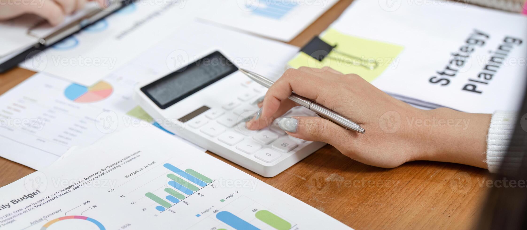 Office worker calculating financial data with charts and a calculator, focusing on budget planning. photo