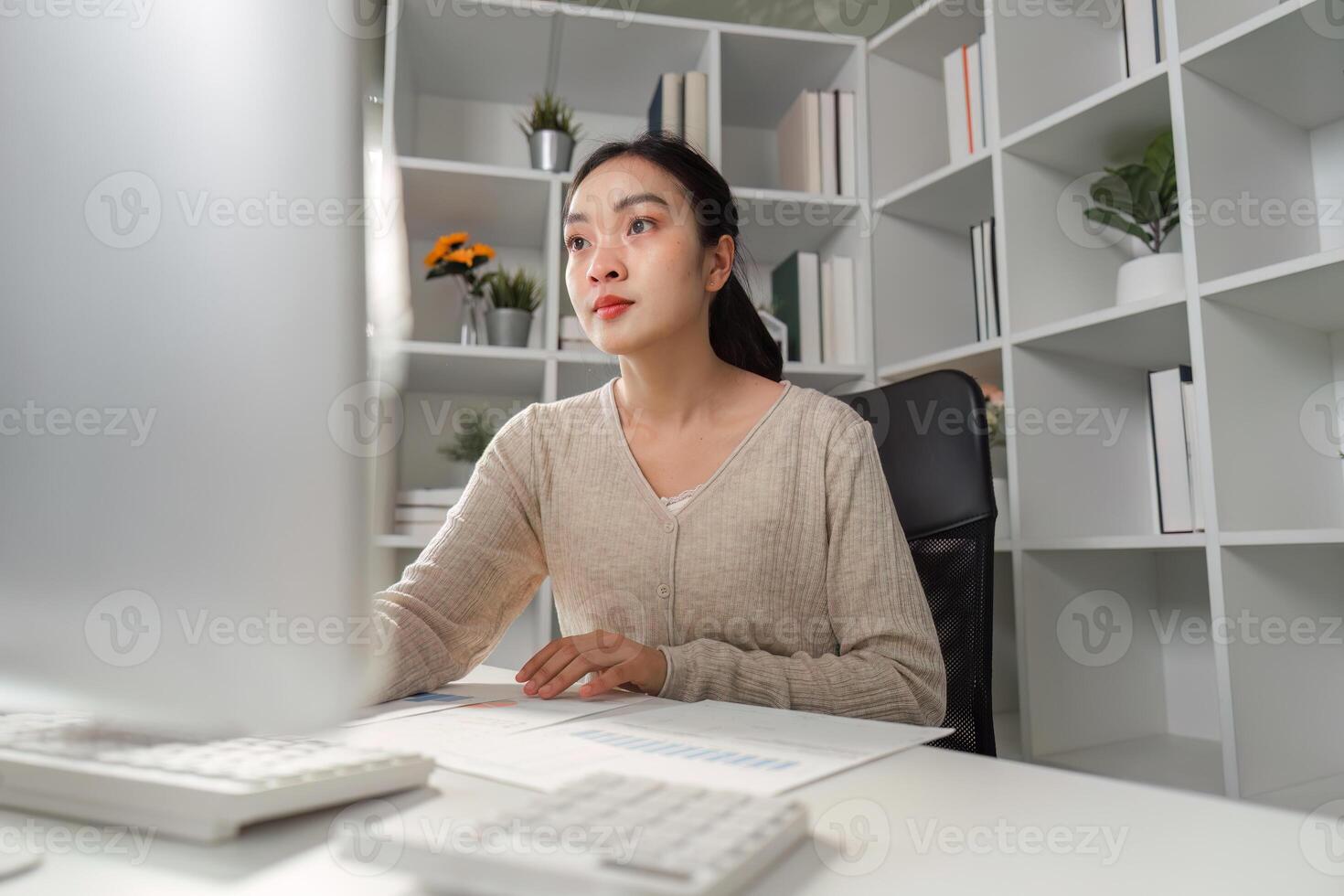 Focused office worker analyzing data and reports on a computer in a modern workspace. photo