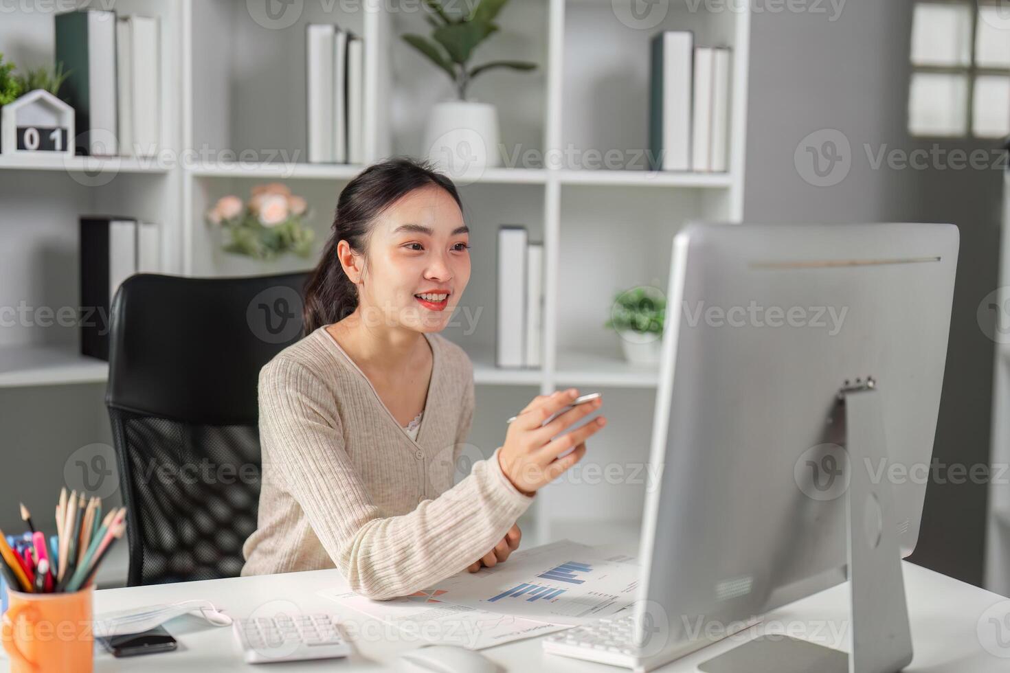 Young office worker smiling while working on a computer, engaging with data and reports. photo