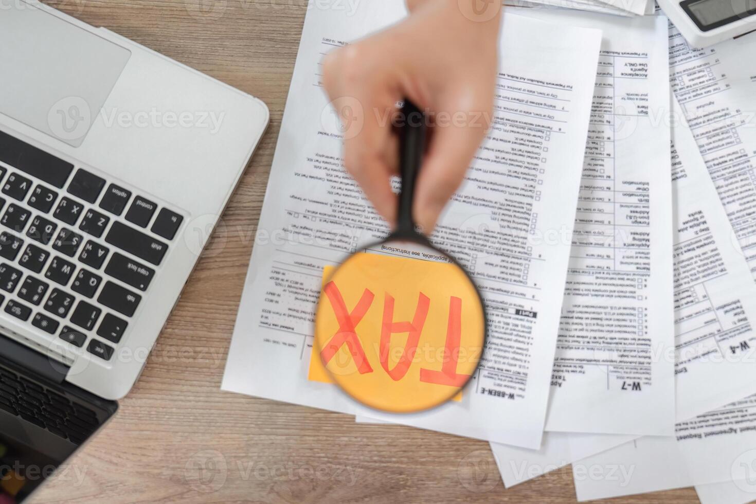 Close-up of hands using a magnifying glass on tax documents, emphasizing important financial information. photo