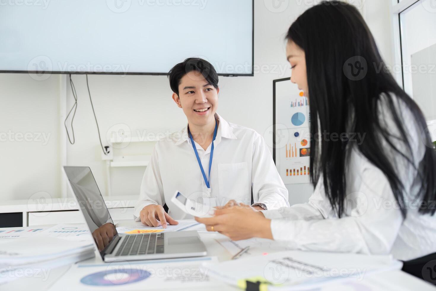 Two professionals smiling and discussing tax plans in a collaborative office environment. photo