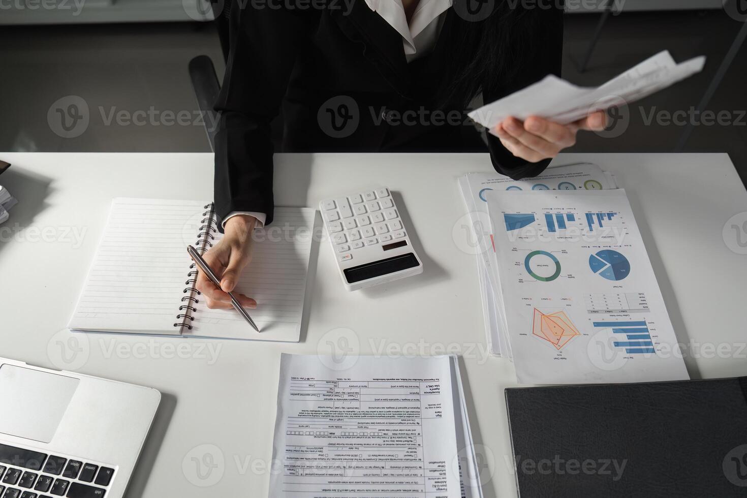 Accountant reviewing financial documents and taking notes with a calculator. photo