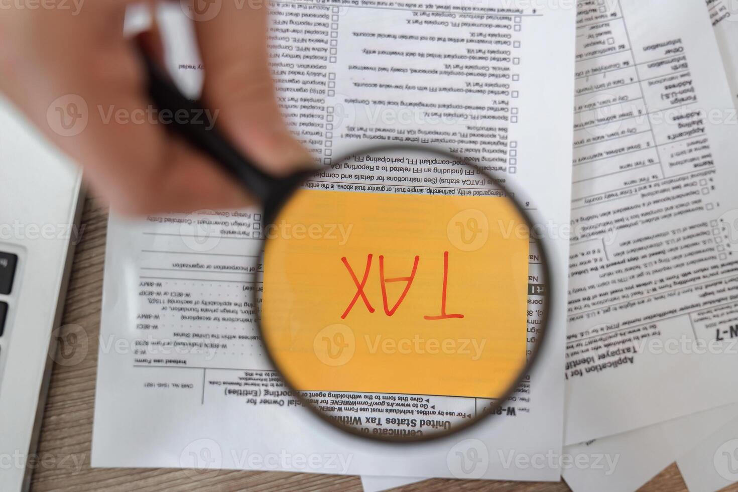 Magnifying glass revealing the word 'TAX' on financial documents, highlighting critical information for filing. photo