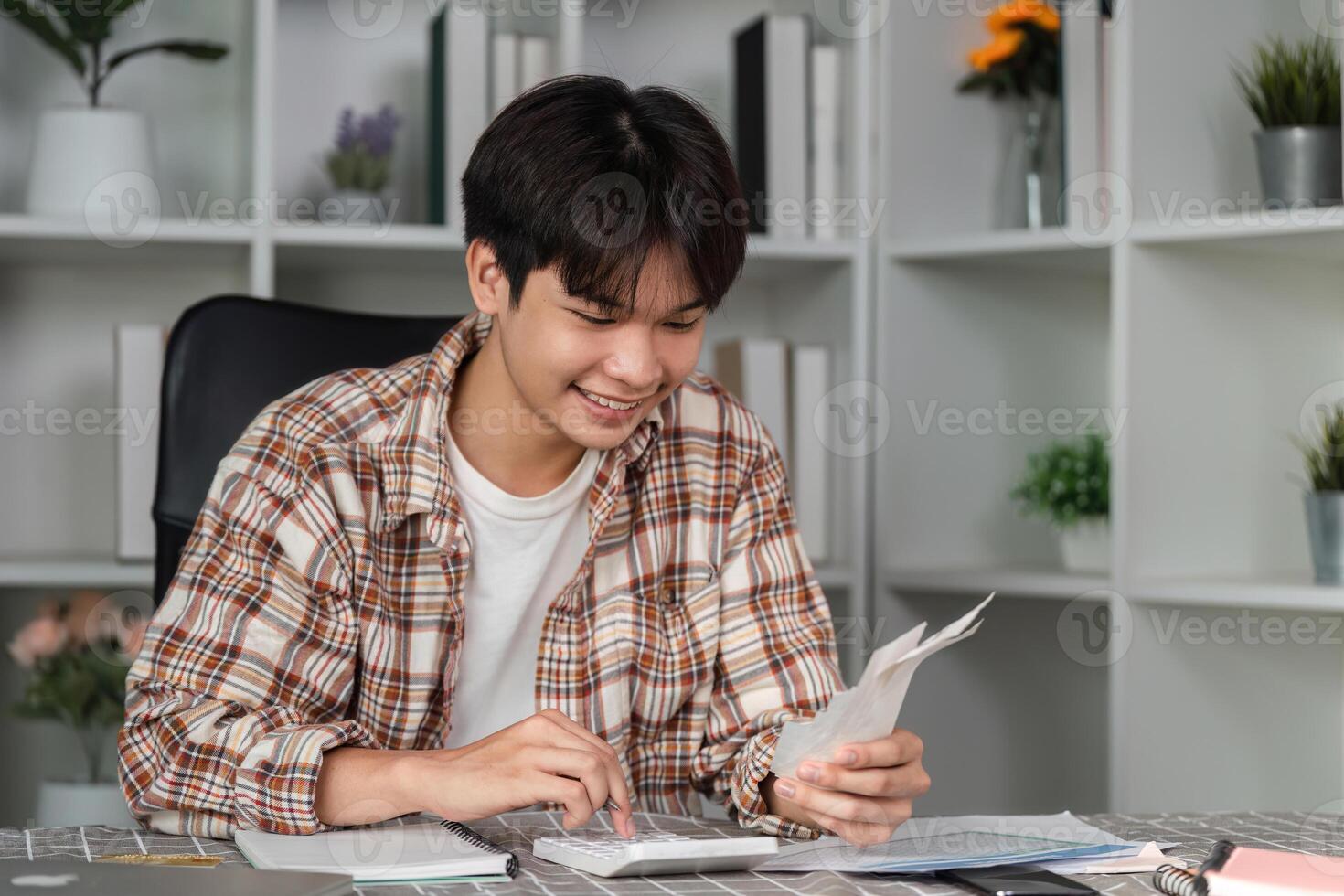 Young man managing finances with smartphone and credit card, smiling and celebrating success. photo