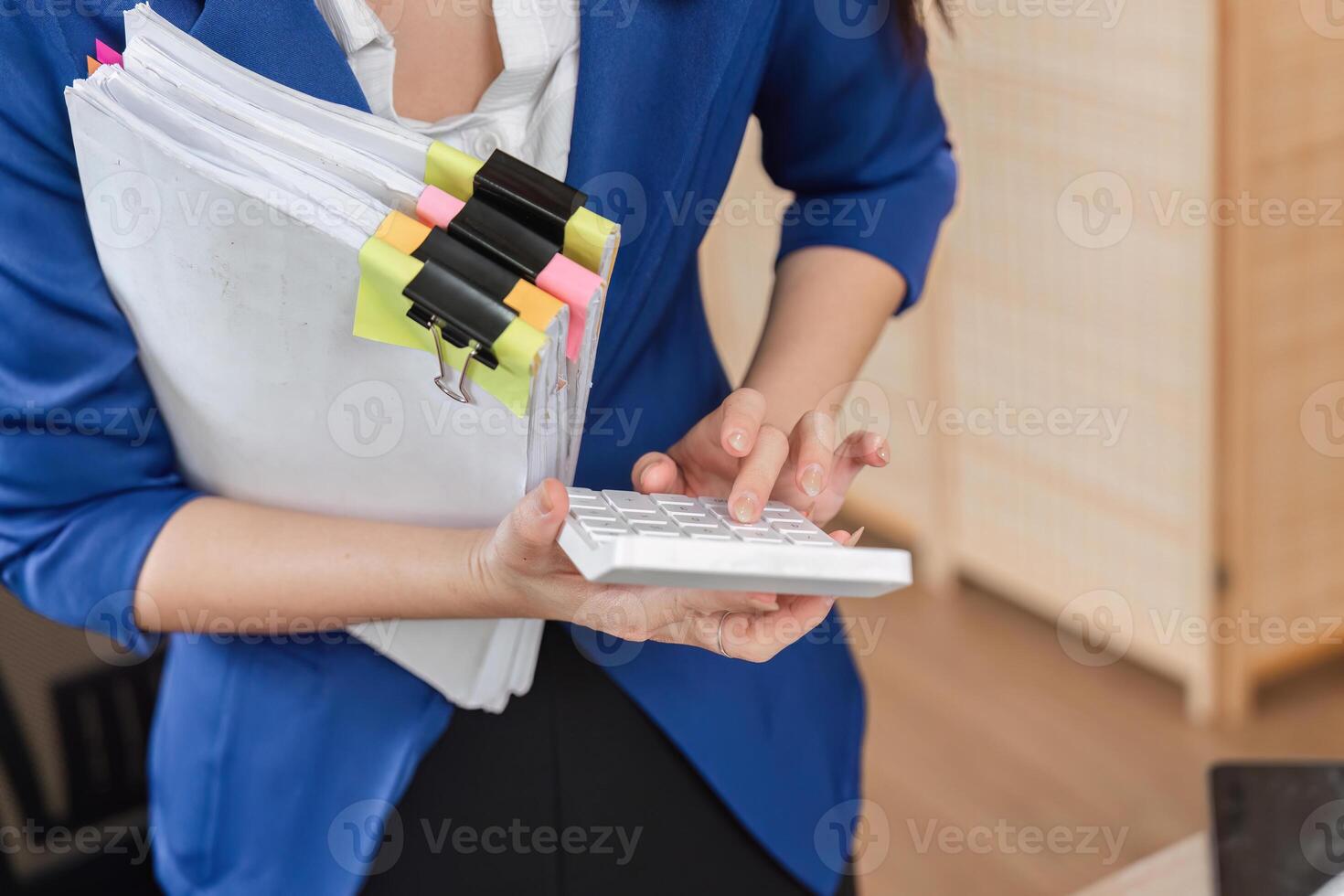 Accountant inputting data on calculator while holding tax documents photo