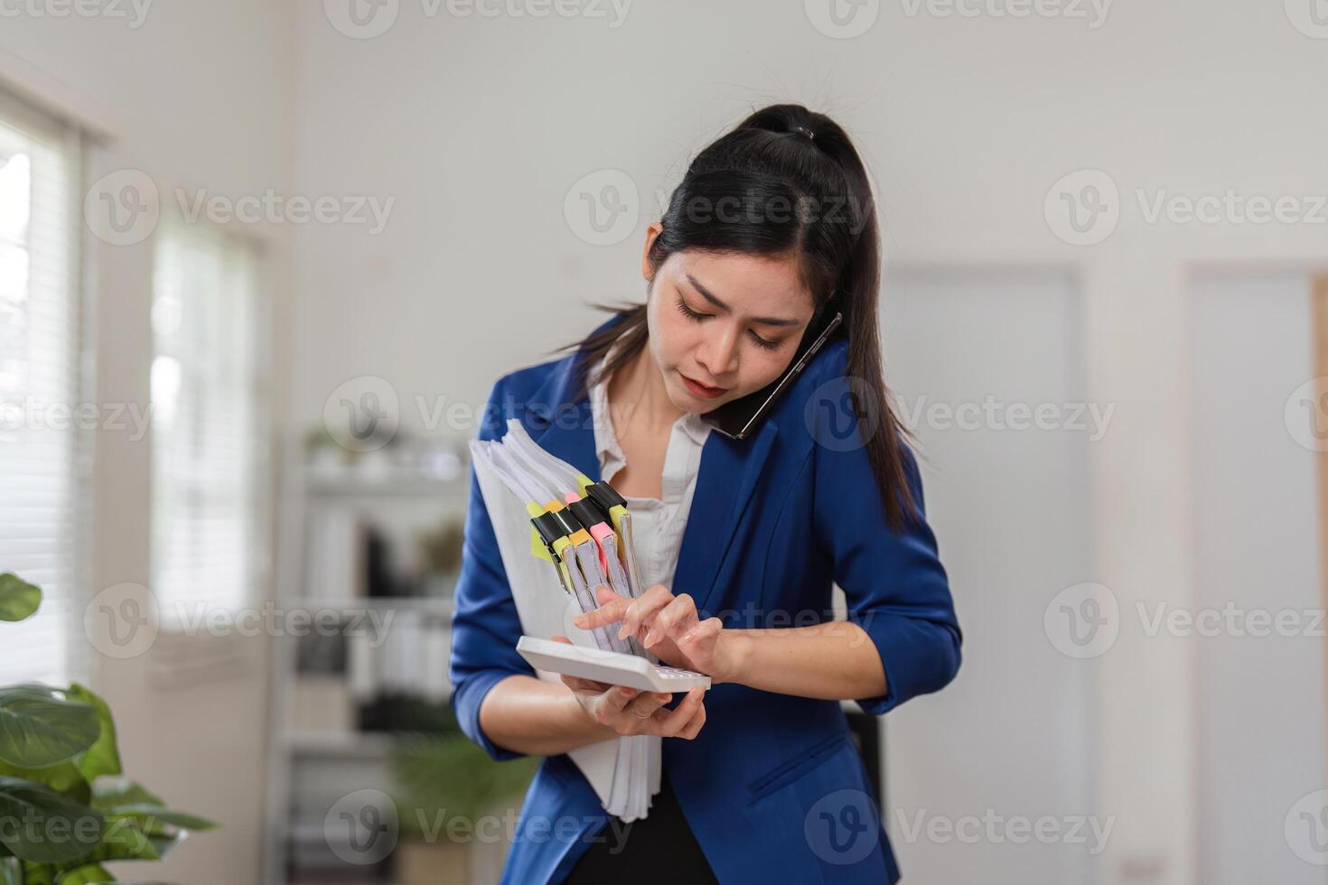 Accountant on a call while checking tax files and documents in her office. photo