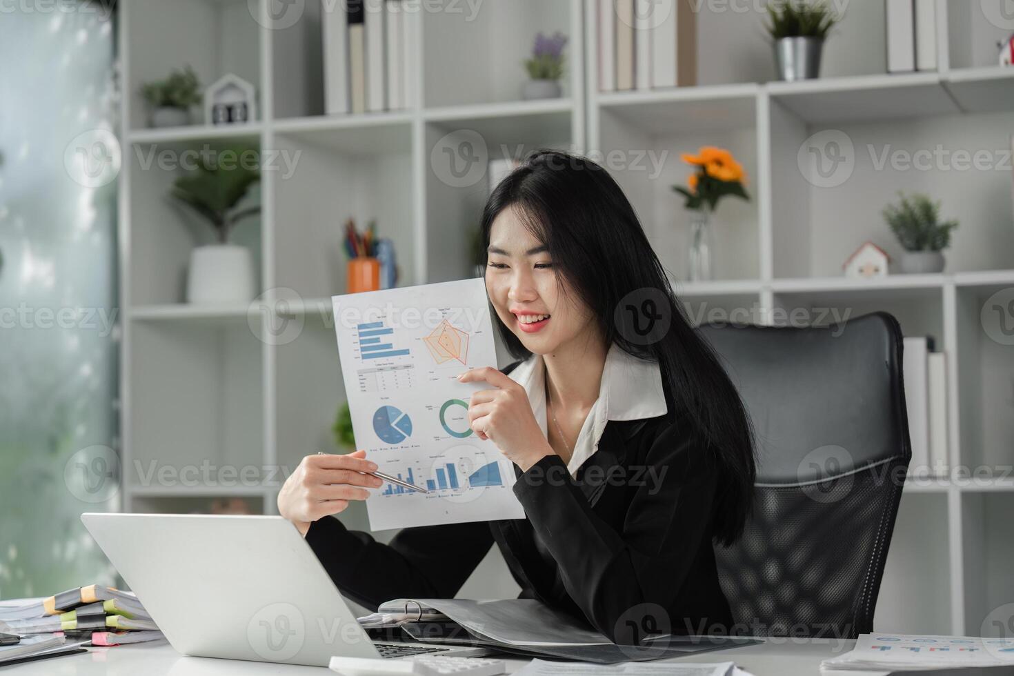 Businesswoman reviewing financial charts and smiling in a contemporary office. photo