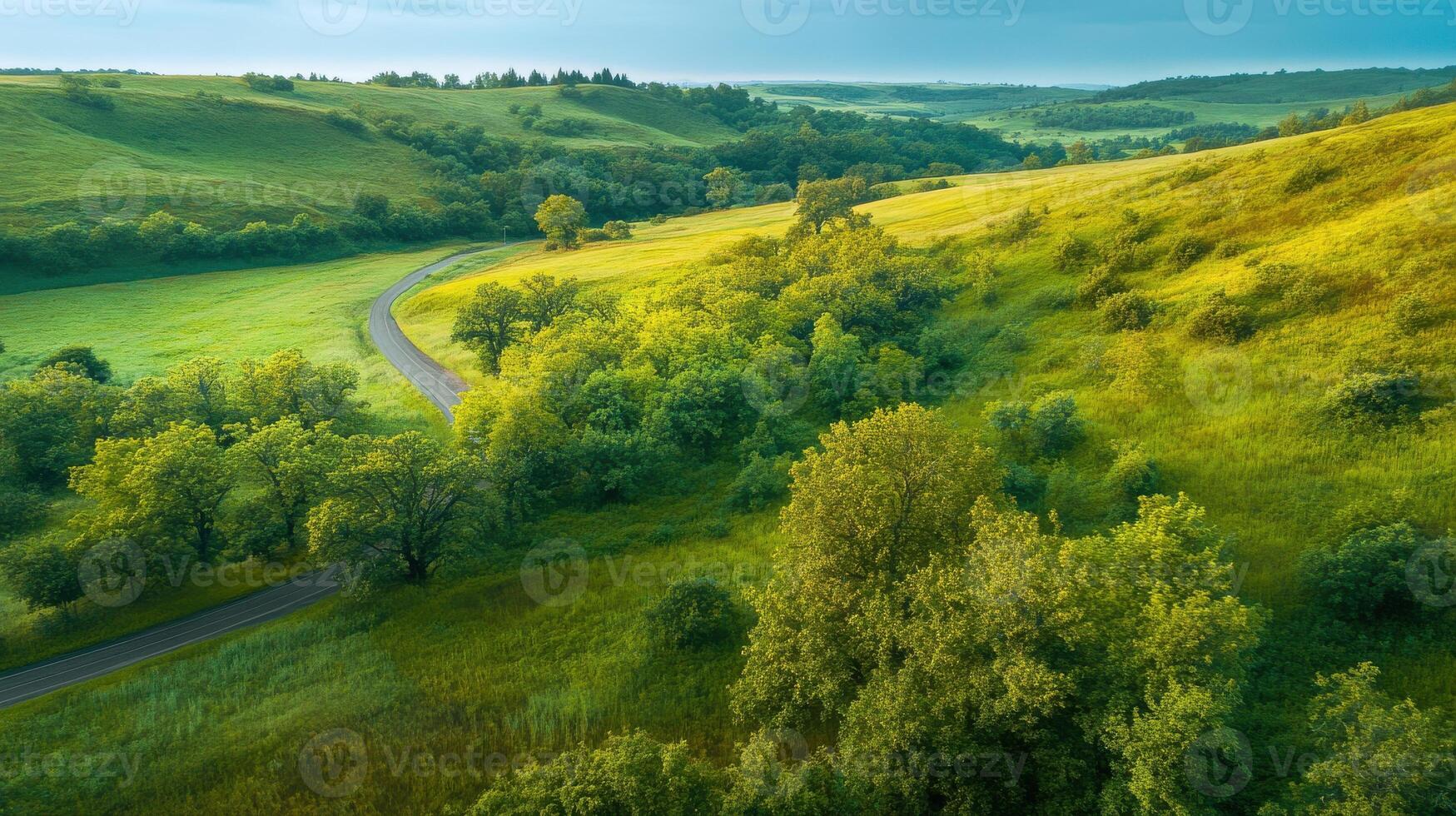 Tranquil landscape of rolling hills and green valleys with winding road and trees photo