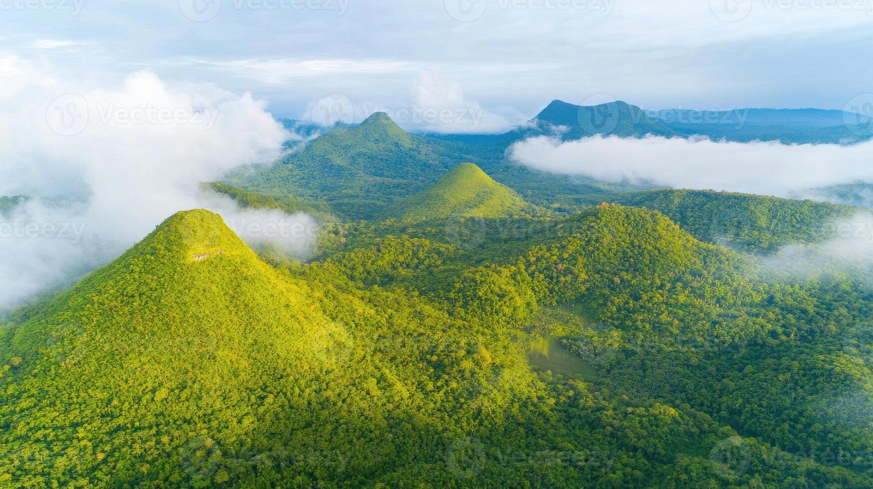 Aerial view of lush green mountains surrounded by misty clouds in tropical landscape photo