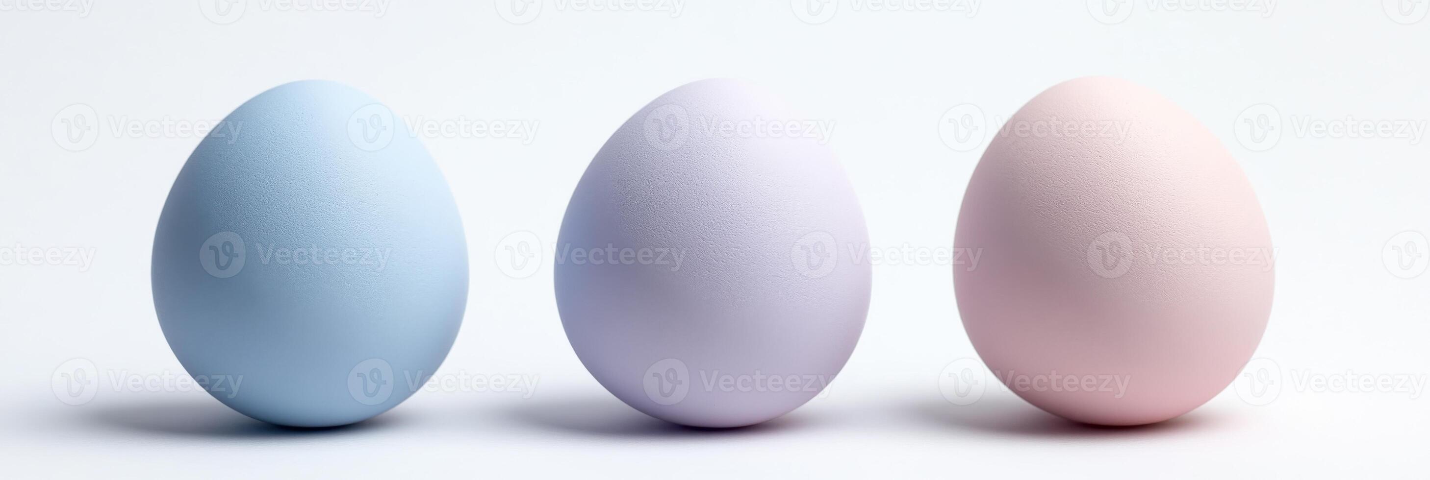 Three pastel colored eggs in blue, purple, and pink on a white background photo