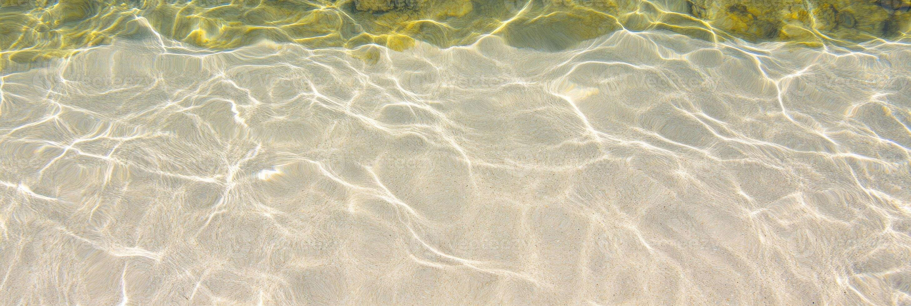 Sunlit ocean water texture creating rippling sand patterns by the shore photo