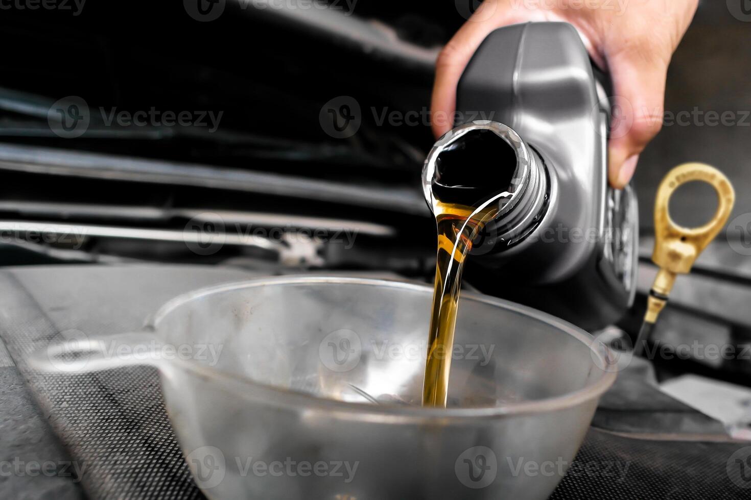 Pouring motor oil during car maintenance , The mechanic poured engine oil into a funnel on the engine oil fill port , Car maintenance concept photo
