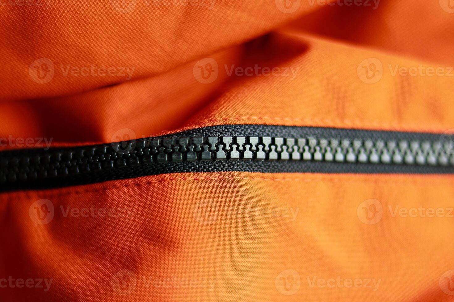 Zipper on the orange jacket. Close up view of zipper. photo