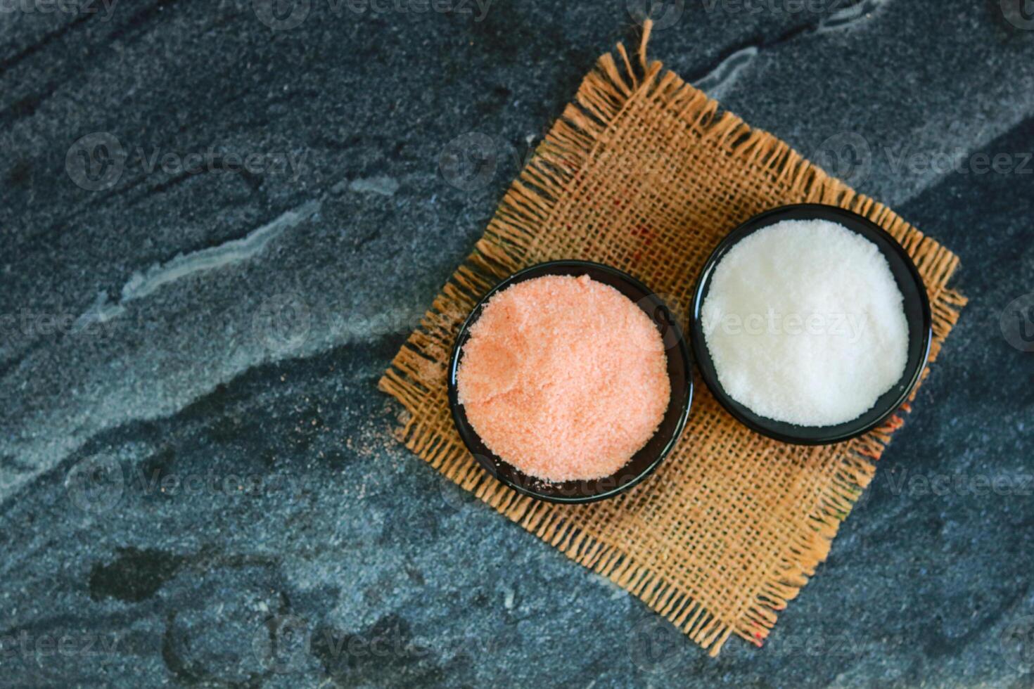 Close up of pink and white salt in a bowl on a black stone background with copy space photo
