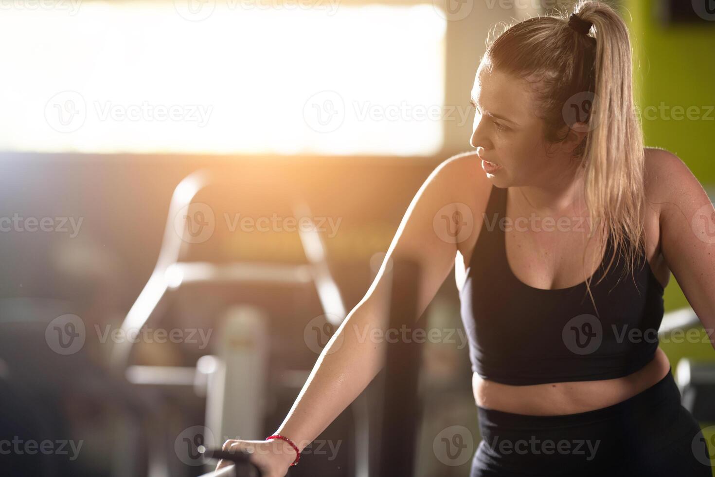 Woman Running on Treadmill in Gym.A fit woman wearing a purple sports outfit is running on a treadmill in a gym. She has a focused yet relaxed expression, with gym equipment and a warm light in the photo