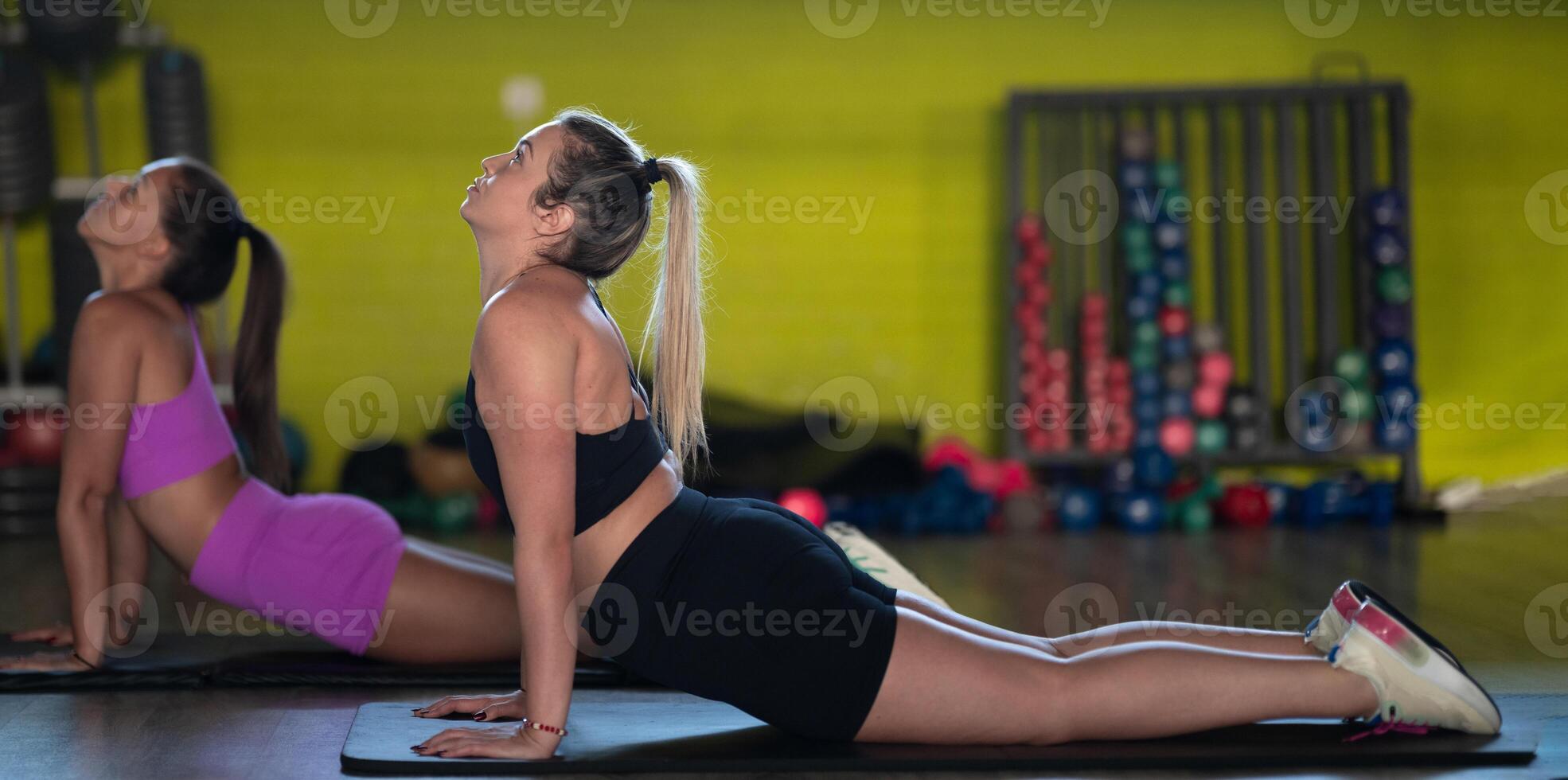 Two fitness women stretch together in the gym, supporting each other in their journey towards flexibility and wellness. photo