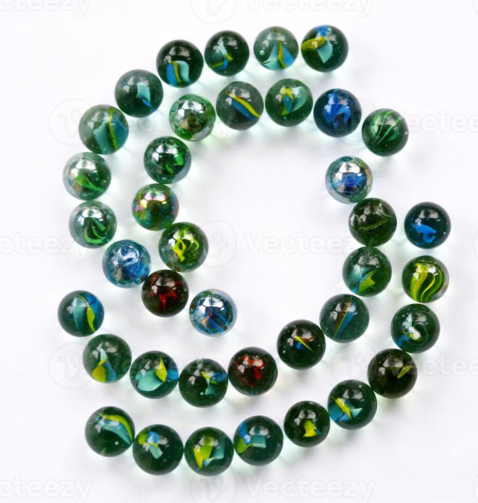 A collection of toy marbles arranged in a unique half-circle with a white back. art background. Unique art. Unique photo. Toy marbles design. photo